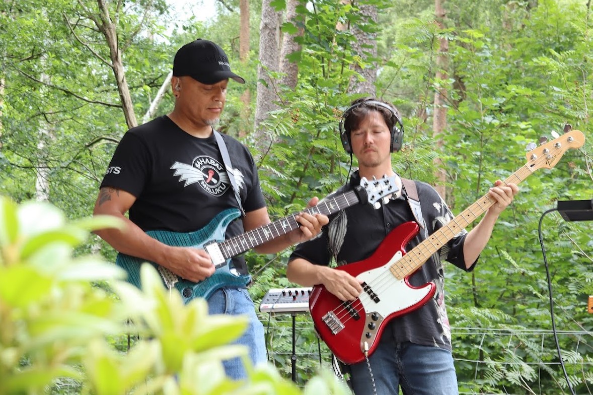 man watching a band on the stage wearing a red t-shirt and black hat.